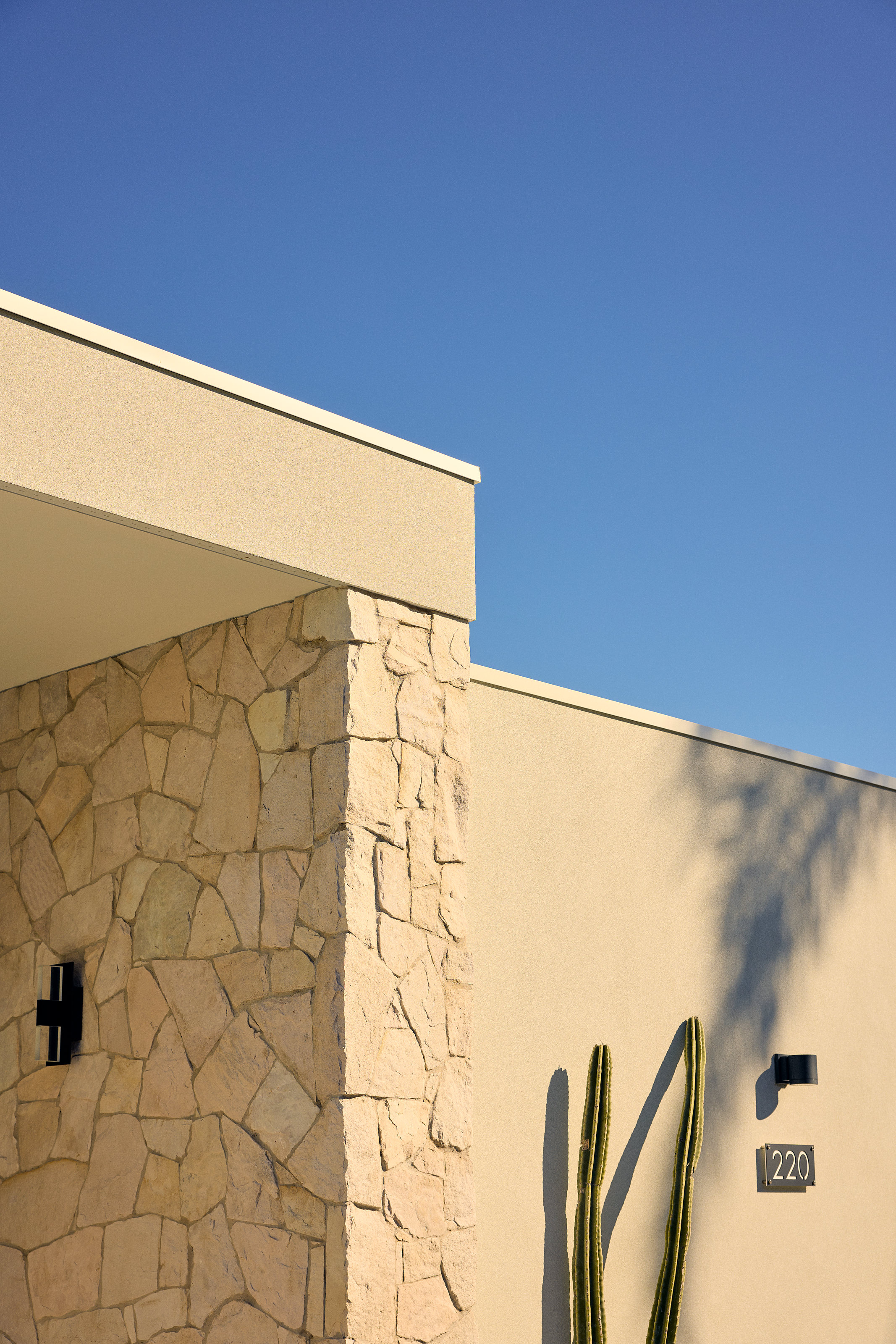 Palme Hus, rendered wall and stone pier at the entry, cactus and house number